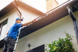 A man on a ladder doing a gutter inspection