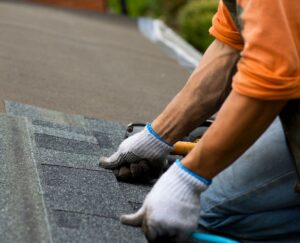 A person placing new shingles on a roof